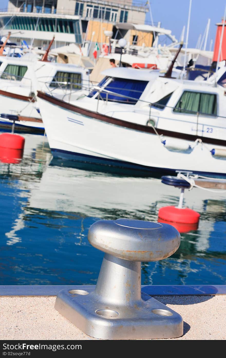 Boats moored in the sunny afternoon at a marina . Liguria - Italy. Shallow dof, focus on Mooring cleats. Boats moored in the sunny afternoon at a marina . Liguria - Italy. Shallow dof, focus on Mooring cleats