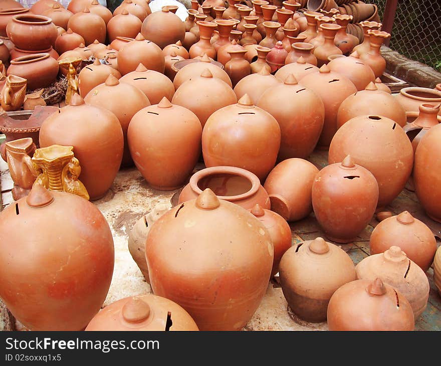 A group of different shaped earthen pots, and piggy banks in various shades of orange, made out of clay