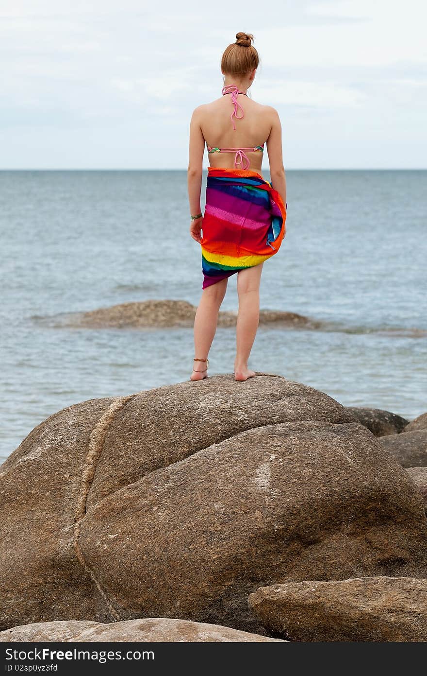 Woman on the beach, in bikini and bath towel with look to the sea