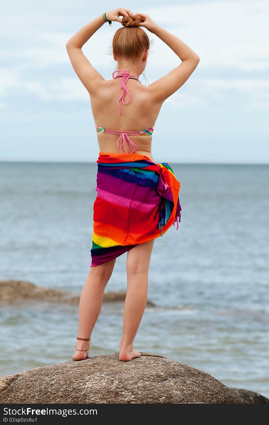 Woman on the beach, in bikini and bath towel with look to the sea