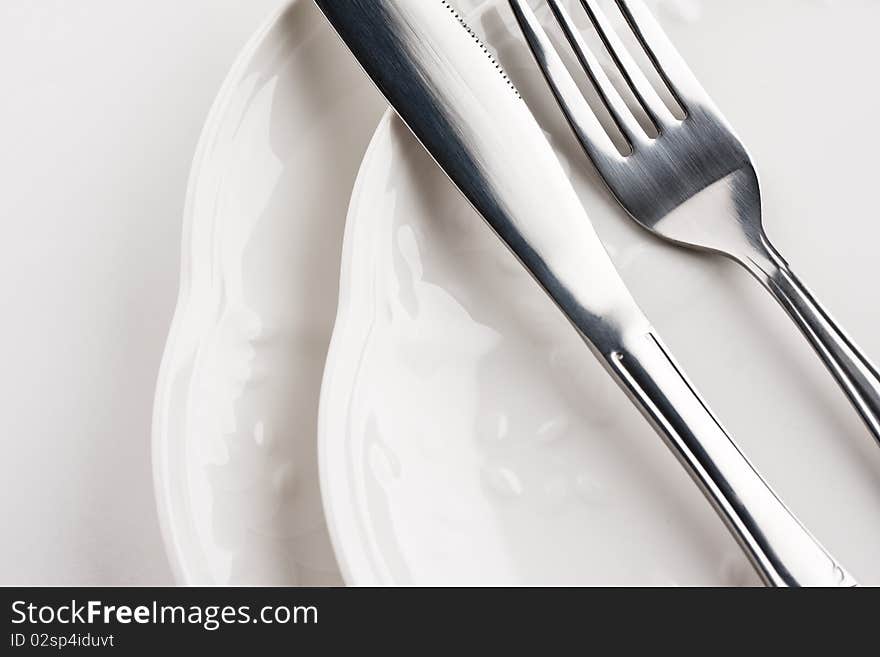 Close up of white dinner plates with silver knife and fork. Close up of white dinner plates with silver knife and fork.