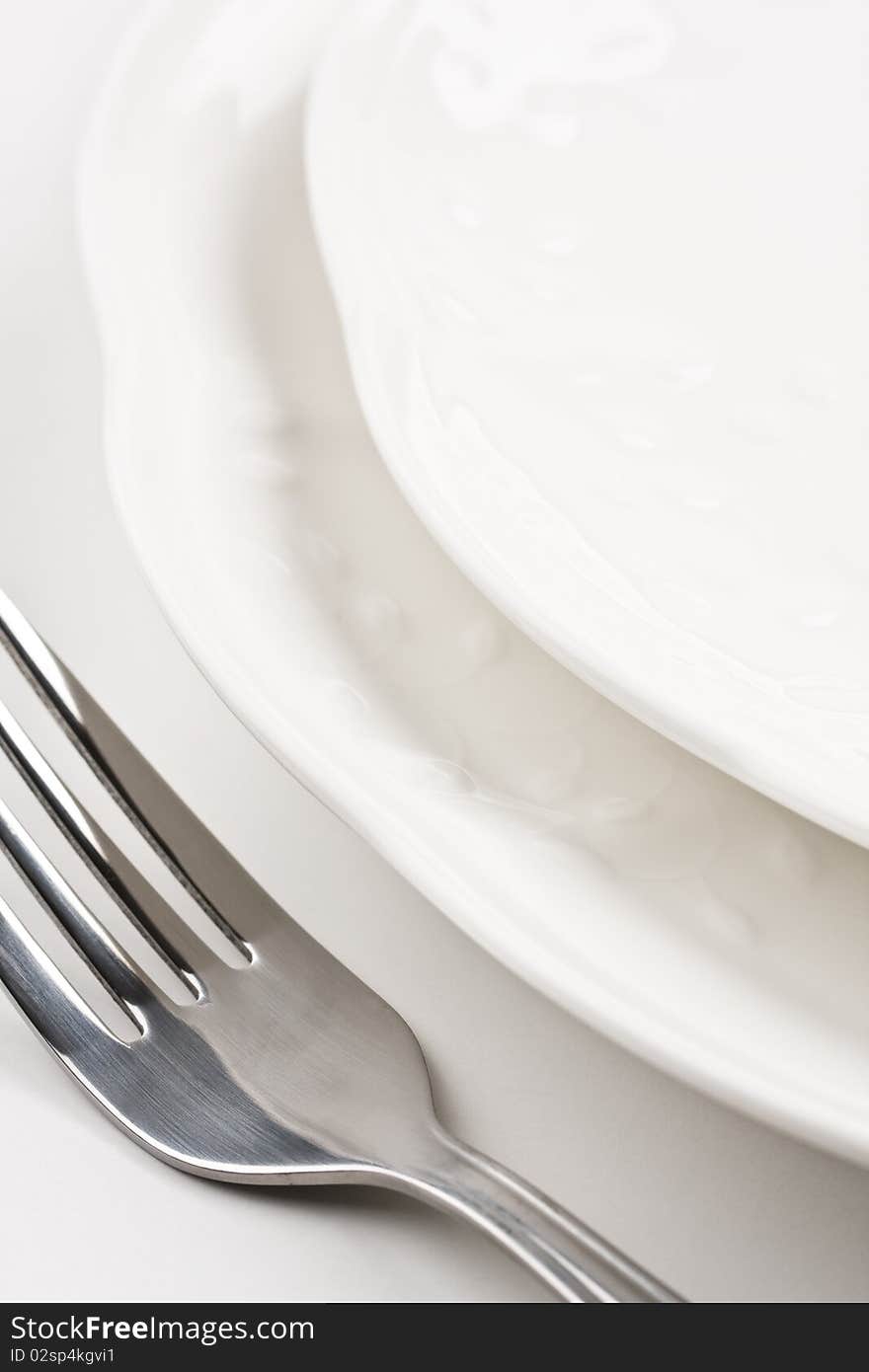 Close up of white dinner plates with silver knife and fork. Close up of white dinner plates with silver knife and fork.