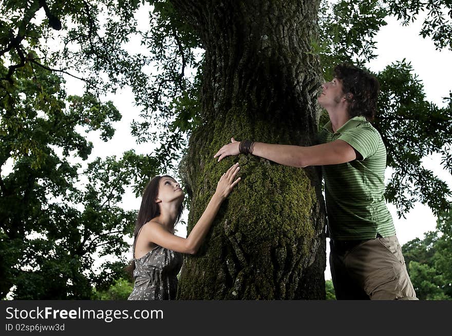 Two nature loving teenagers embracing a tree in a wood, taken in Lipica, Slovenia. Concept: care of nature. Two nature loving teenagers embracing a tree in a wood, taken in Lipica, Slovenia. Concept: care of nature