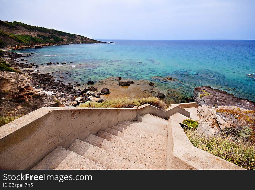 Coast of Sardinia, sea, sand and rocks with blue sky and clouds