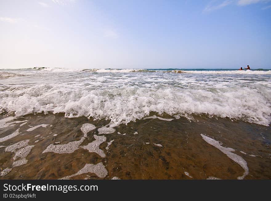 Seashore with waves and foam and blue sky