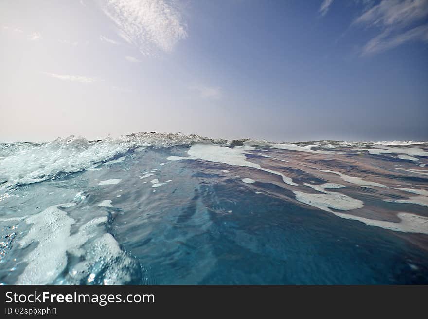 Seashore with waves and foam and blue sky