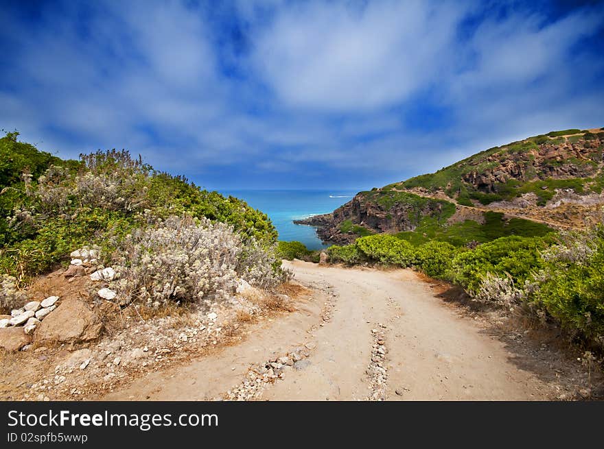 Coast of Sardinia, sea, sand and rocks with blue sky and clouds