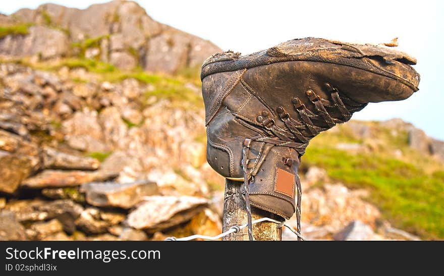 An old worn out boot discarded and retired on mountain post. An old worn out boot discarded and retired on mountain post