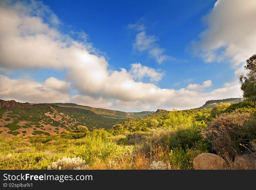 Coast of Sardinia, sea, sand and rocks with blue sky and clouds