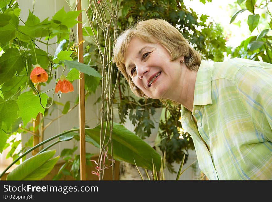 An elderly woman  in a winter garden looks at a flower with a delight