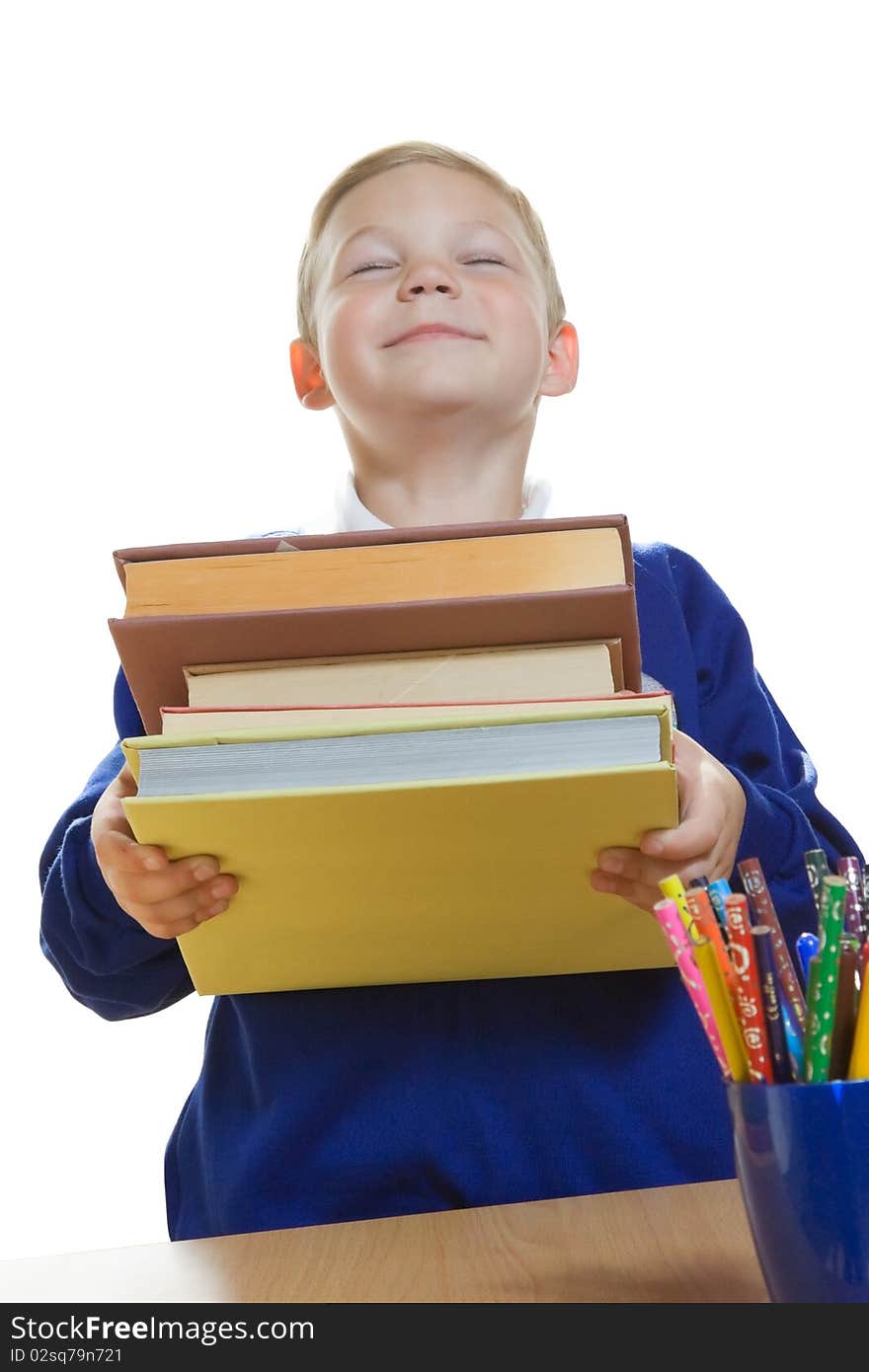 Smiling young boy in school uniform holding a heap of books. Smiling young boy in school uniform holding a heap of books