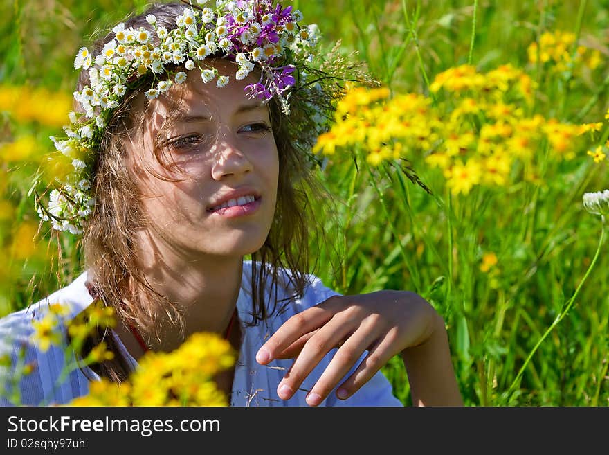 Russian girl in a wreath from camomiles is in a wheaten field