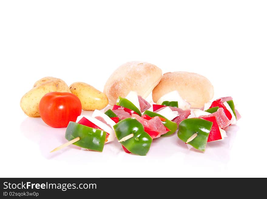 Barbecue meat skewers decorated with vegetables and bread isolated over white. Barbecue meat skewers decorated with vegetables and bread isolated over white