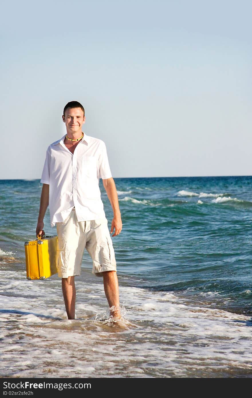 Man with yellow suitcase on beach