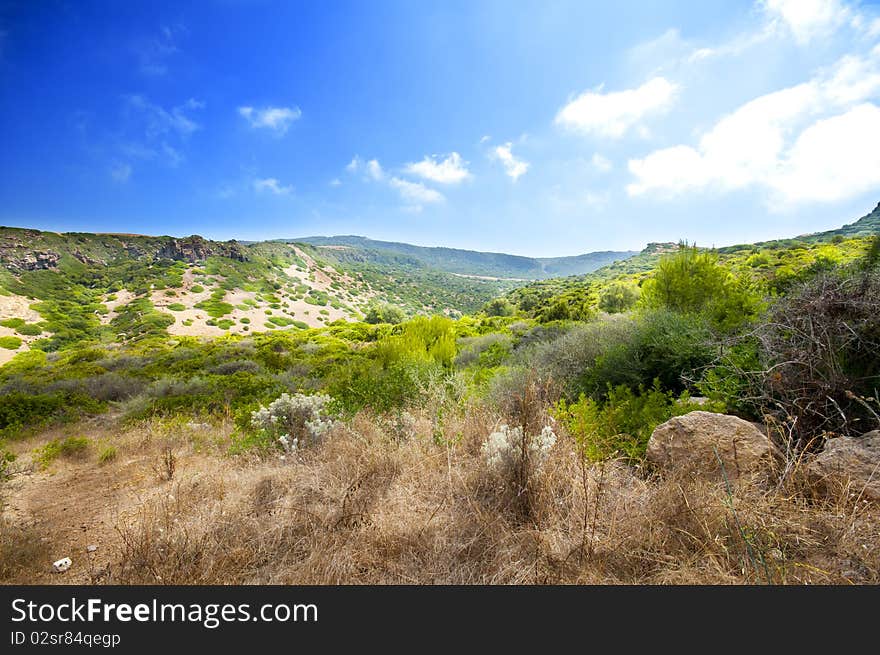 Coast of Sardinia, sea, sand and rocks with blue sky and clouds