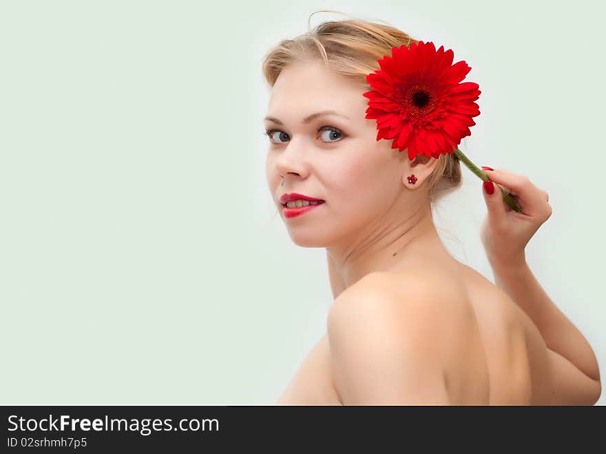 Portrait of the young beautiful girl holding a red flower at itself on a head. Portrait of the young beautiful girl holding a red flower at itself on a head