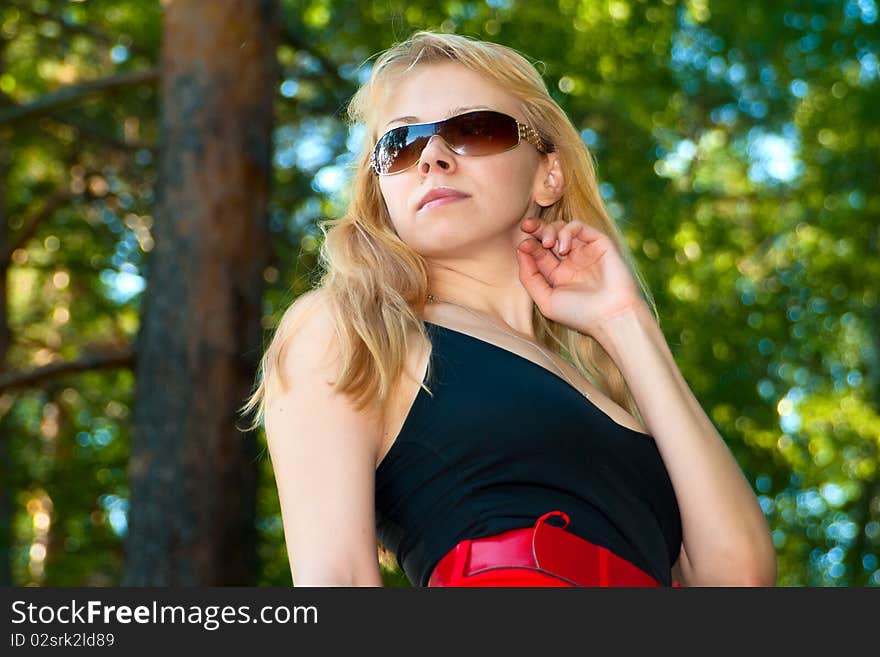 Portrait of the attractive young girl in sun glasses against green woo. Portrait of the attractive young girl in sun glasses against green woo