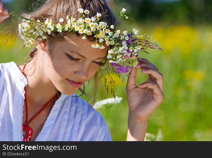 Russian girl in a flower field and a wreath on a head