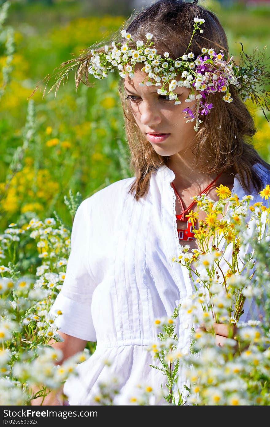 Russian girl in a flower field and a wreath on a head