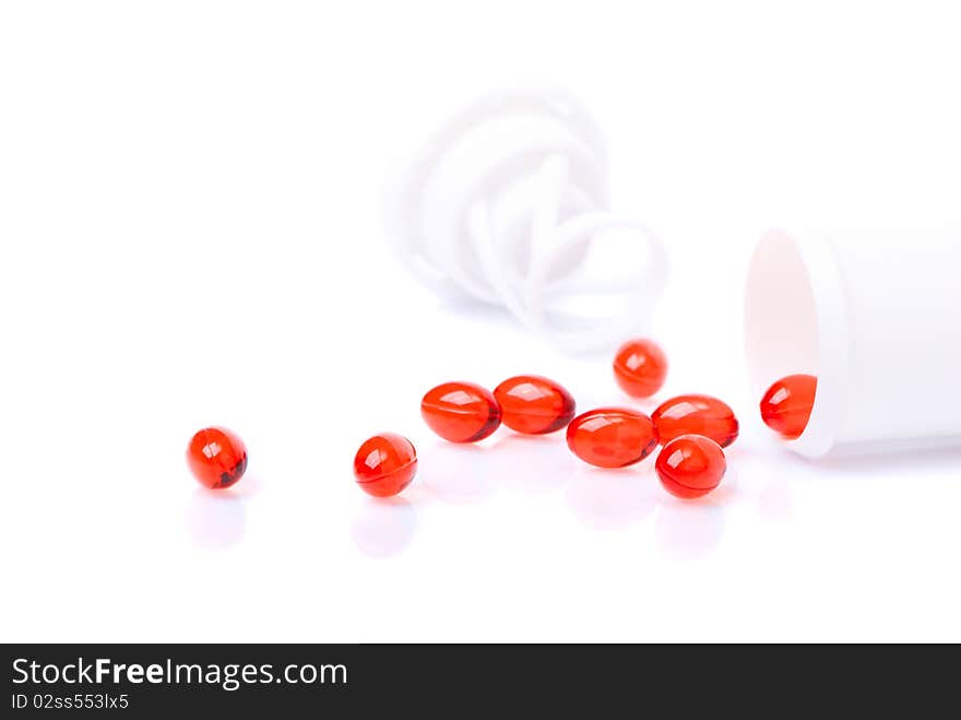 Red tablets scattered from the bottle isolated over white background. Red tablets scattered from the bottle isolated over white background