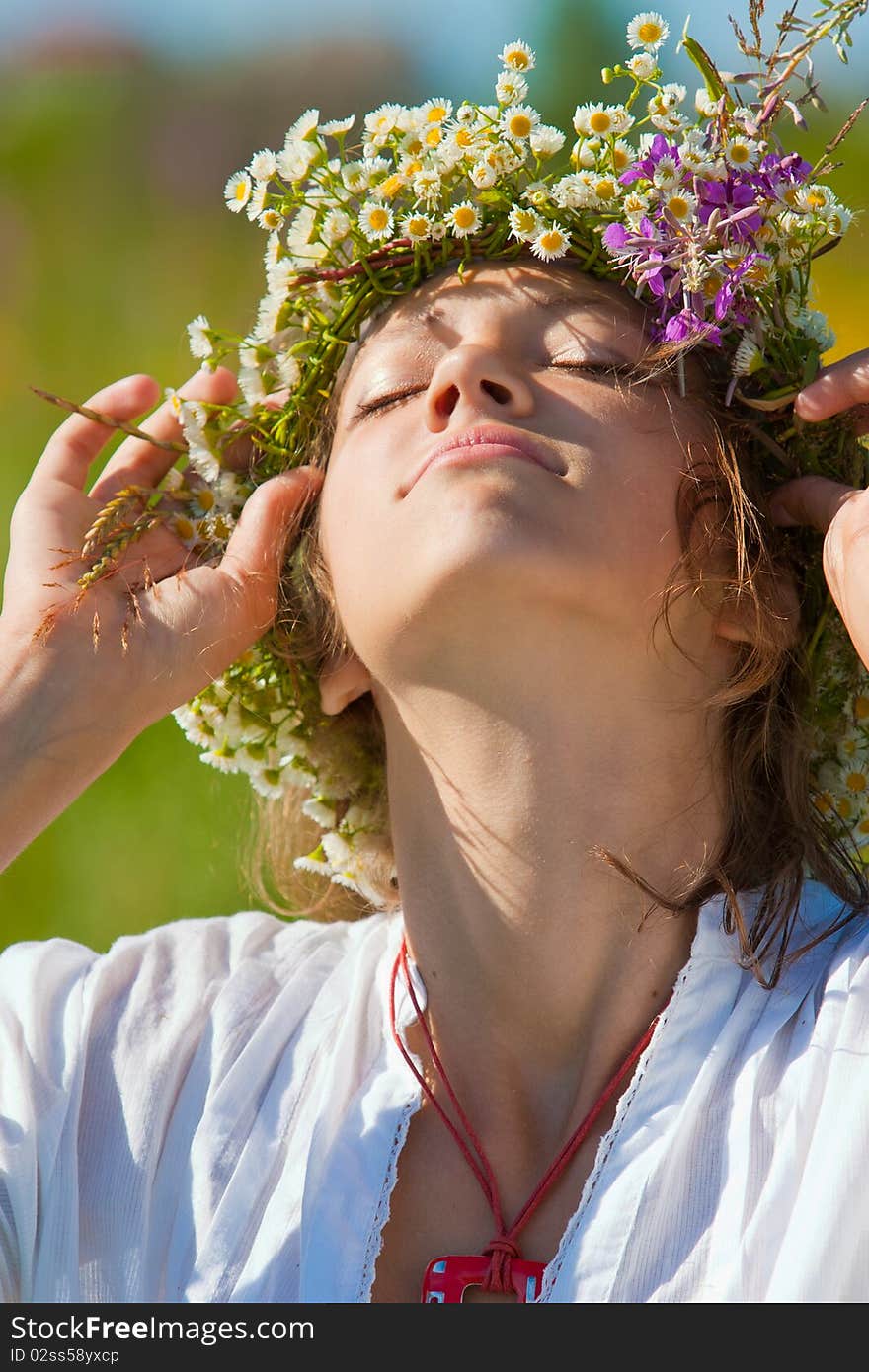 Russian girl in a flower field and a wreath on a head