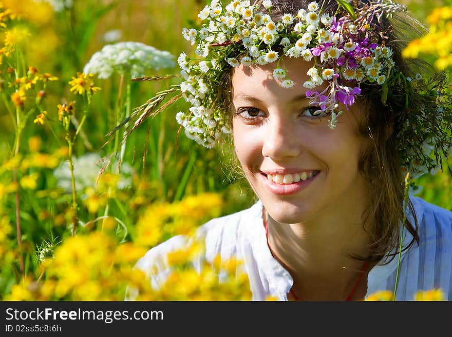 Russian girl in a flower field and a wreath on a head