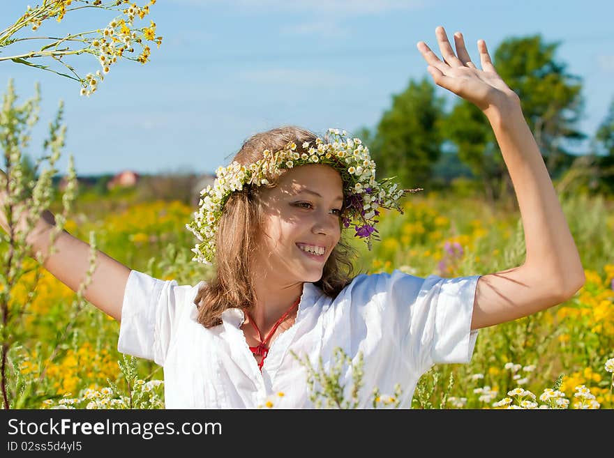 Russian girl in a flower field and a wreath on a head