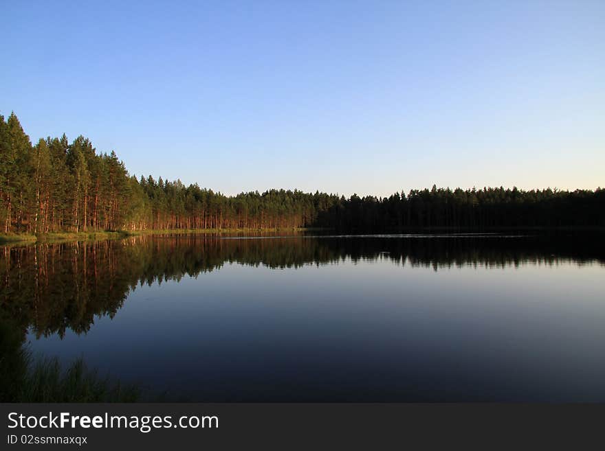 Beautiful Russian deep lake. Summer day. Clearly.The pines are reflected in the water.