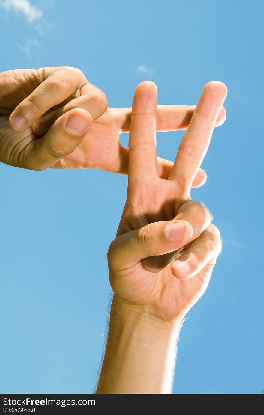 Photos of male fingers, which show the lattice, against the blue sky. Photos of male fingers, which show the lattice, against the blue sky