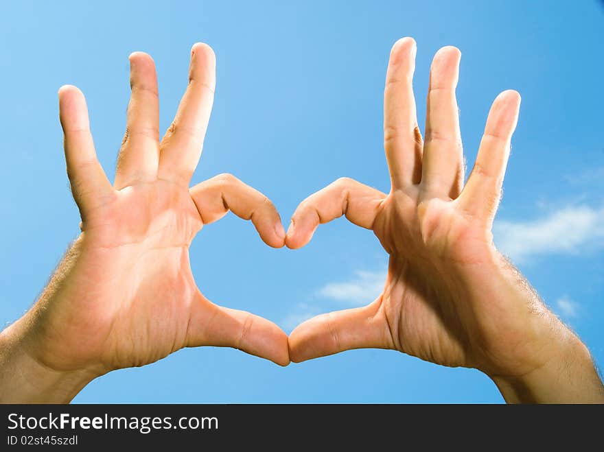 Photos of male hands, folded in the shape of the heart, against the blue sky. Photos of male hands, folded in the shape of the heart, against the blue sky