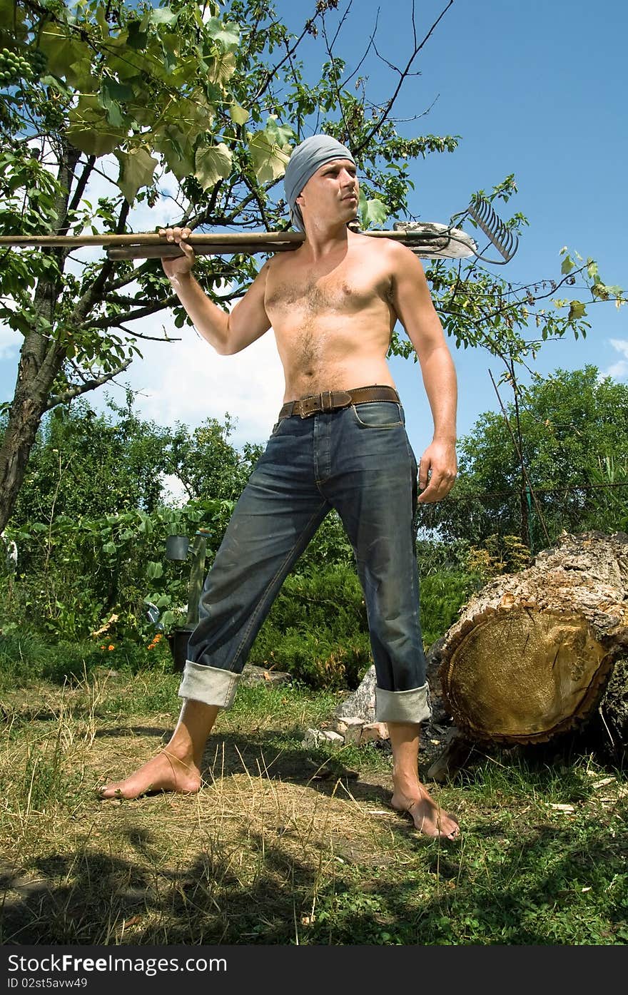 Photo of a young man with a spade and rake on the background of nature. Photos made with the use of special effects.