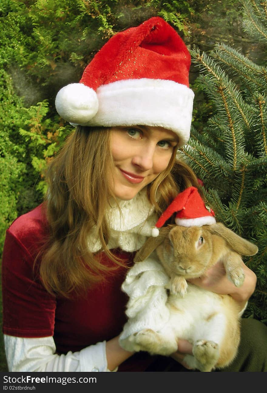 Girl and bunny in christmas hats. Girl and bunny in christmas hats