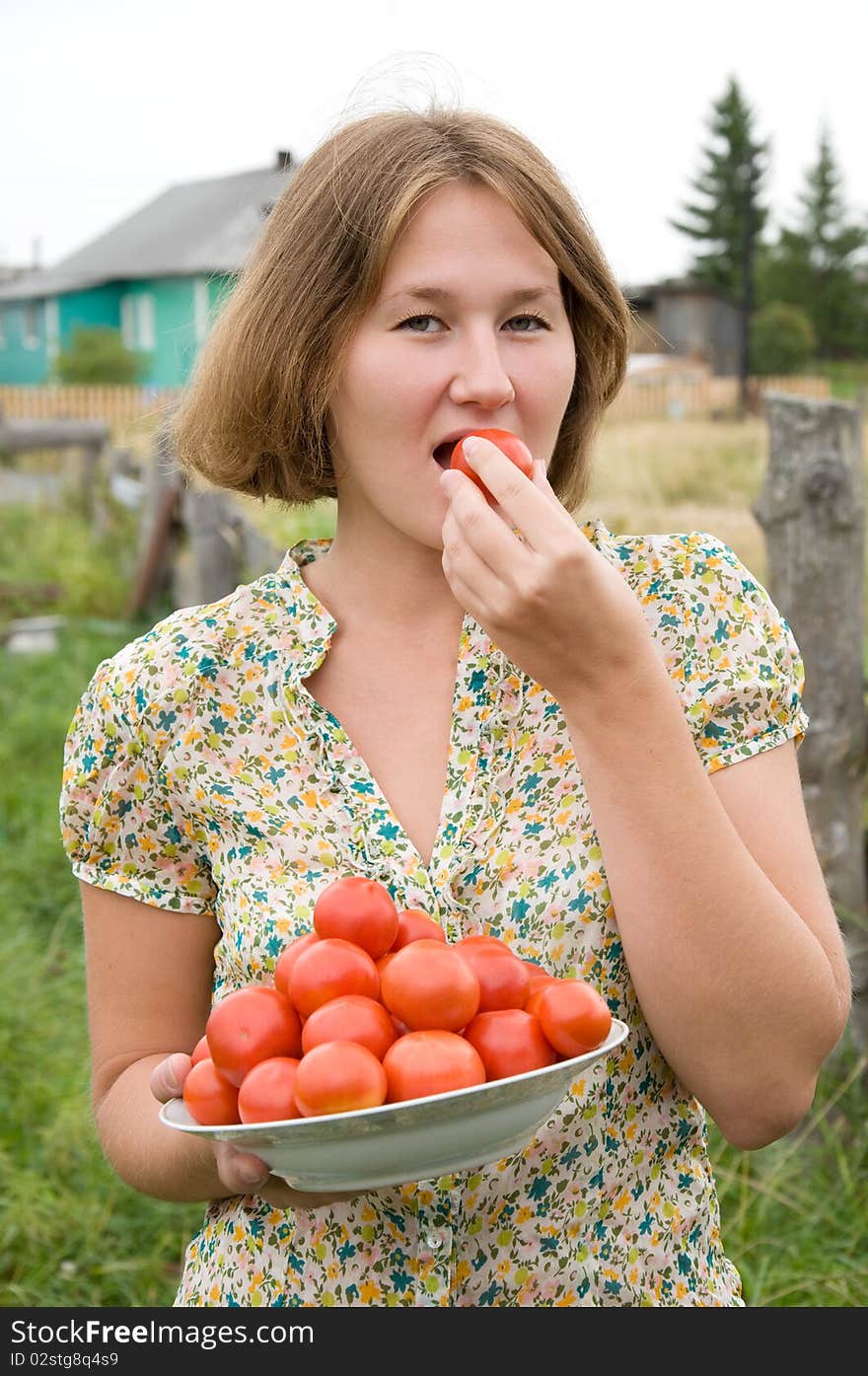 Attractive farmer is tasting harvest of tomatoes