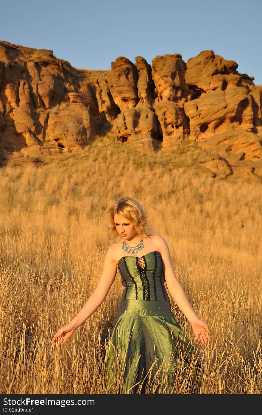 Attractive woman in a long green dress walking by steppe. Attractive woman in a long green dress walking by steppe