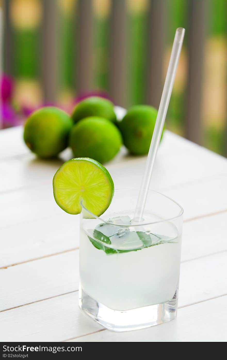 Glass of lime juice and limes in the background