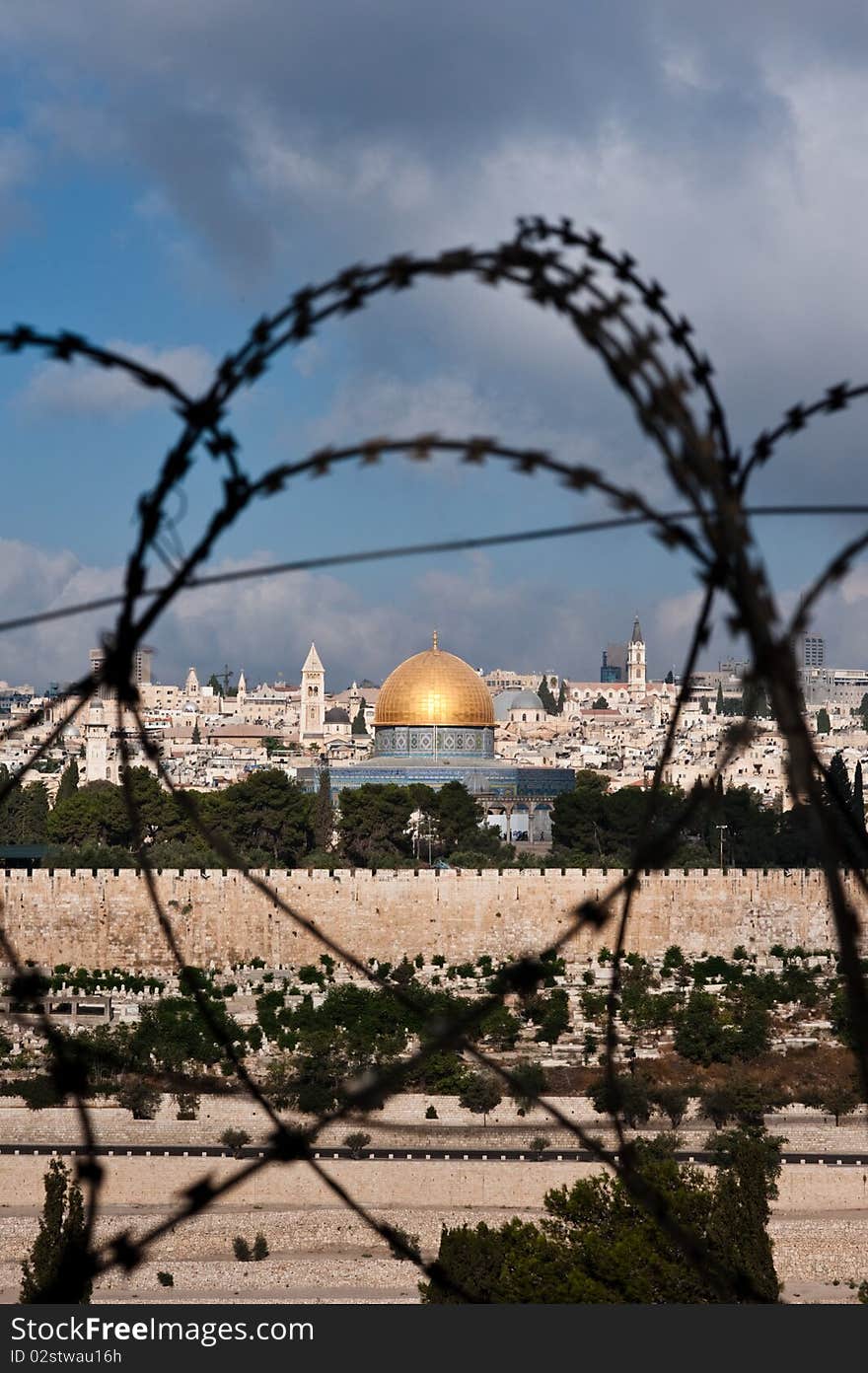 The Old City of Jerusalem, including the Dome of the Rock and various church steeples, seen through coils of razor wire, illustrating the Holy Land's history of division and conflict. The Old City of Jerusalem, including the Dome of the Rock and various church steeples, seen through coils of razor wire, illustrating the Holy Land's history of division and conflict.