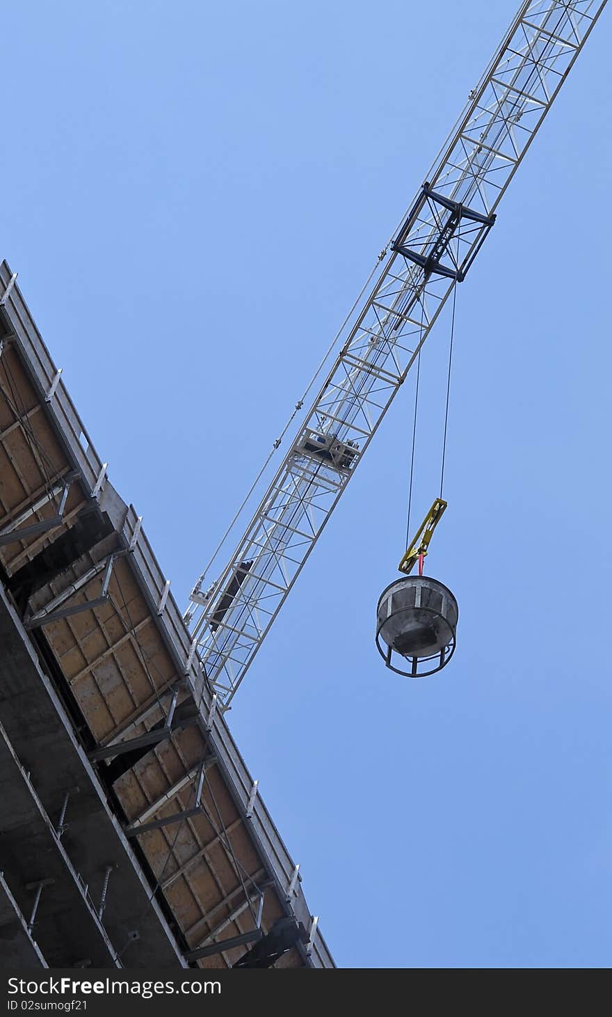 Crane transporting equipment at highrise development, against bright blue sky. Crane transporting equipment at highrise development, against bright blue sky