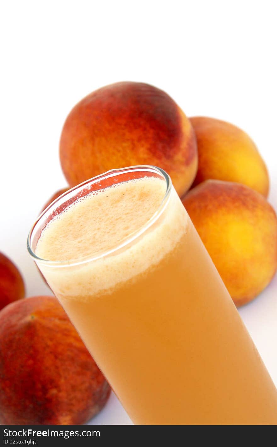 A glass of peach juice in front of peaches isolated on white background. A glass of peach juice in front of peaches isolated on white background.