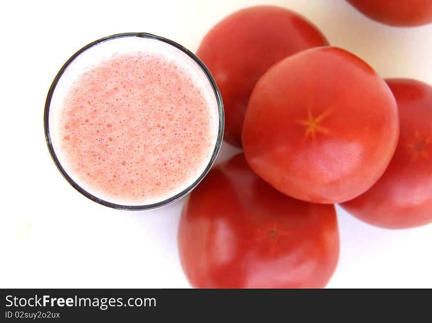 Fresh tomatoes and a glass full of tomato juice isolated on a white background. Fresh tomatoes and a glass full of tomato juice isolated on a white background