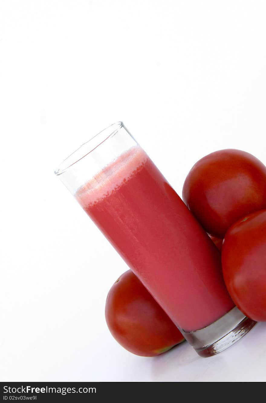 Fresh tomatoes and a glass full of tomato juice isolated on a white background. Fresh tomatoes and a glass full of tomato juice isolated on a white background