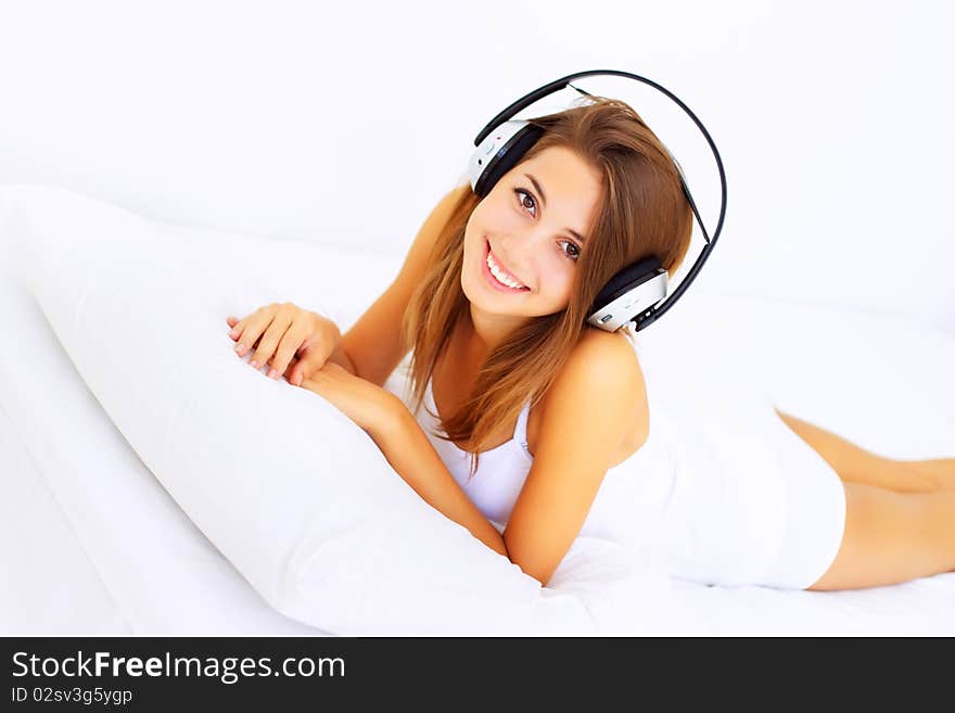 Beautiful girl lying on the bed and listens to music. Beautiful girl lying on the bed and listens to music