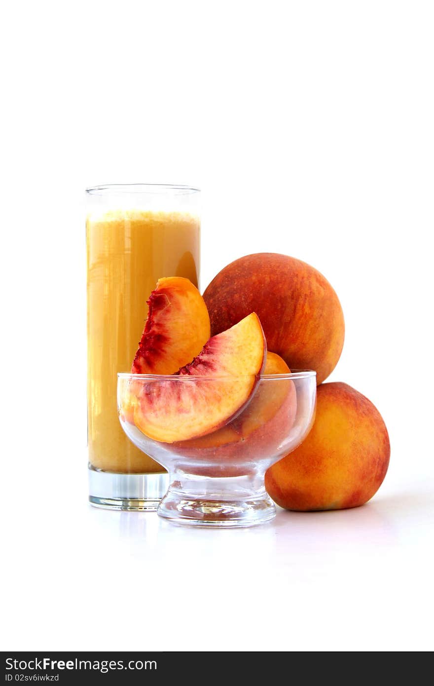 A glass of peach juice in front of peaches isolated on white background. A glass of peach juice in front of peaches isolated on white background.