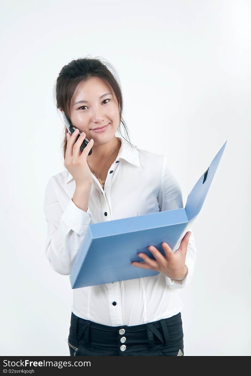 A Beautiful Asian business woman is on the cell phone,who  was carrying a folder