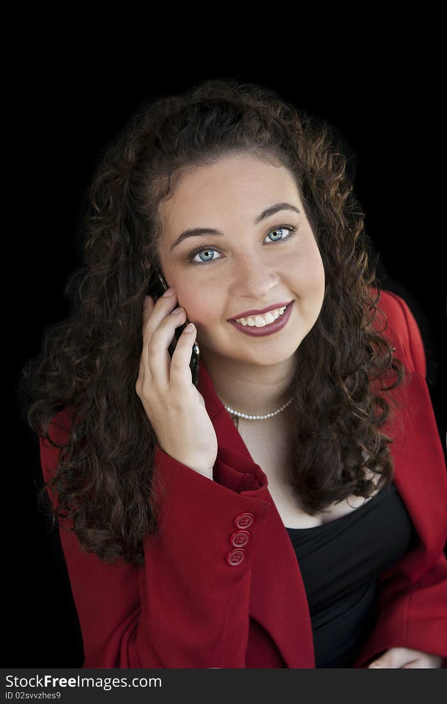 An attractive young business woman talking on cell phone, black background. An attractive young business woman talking on cell phone, black background