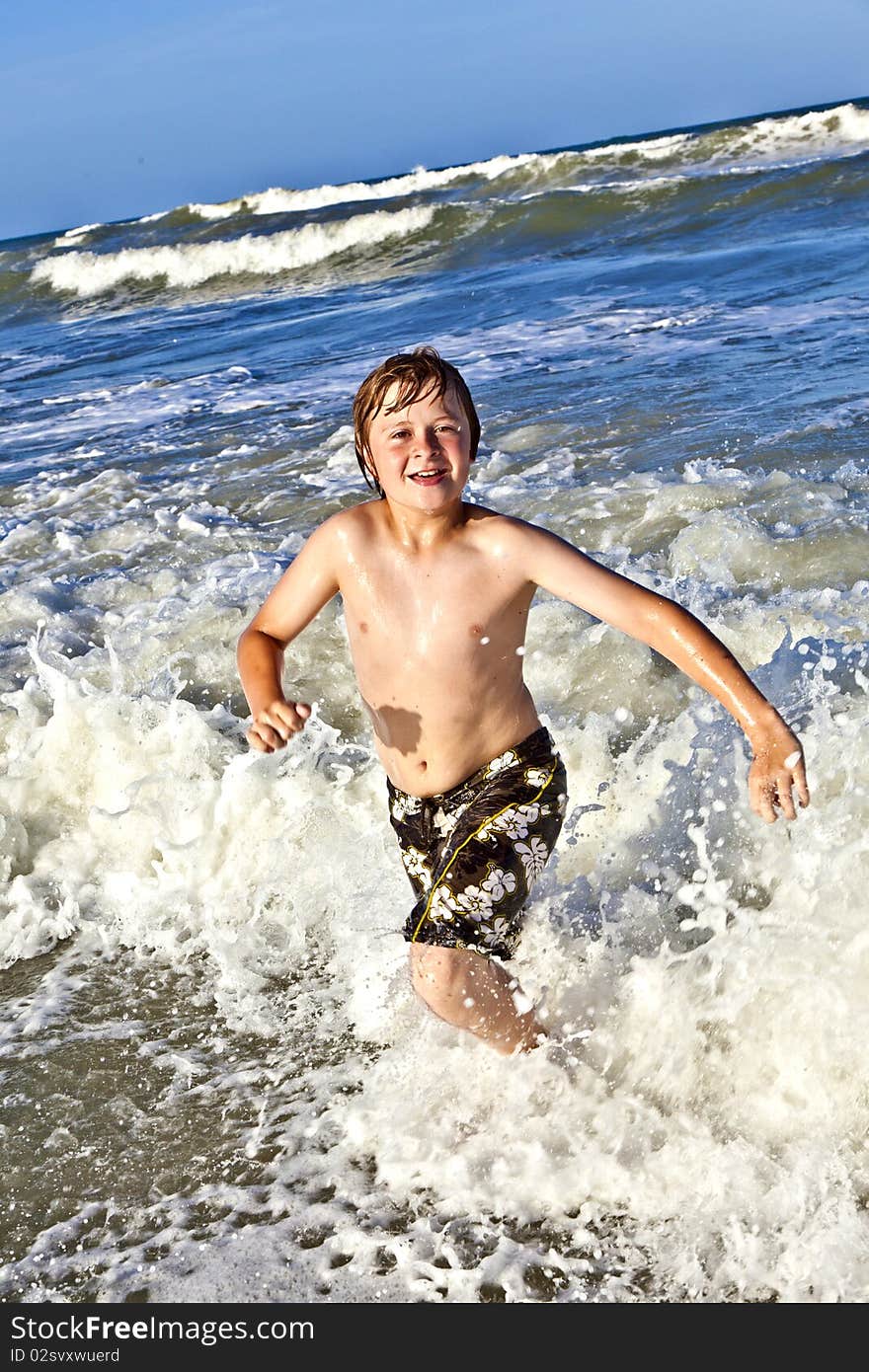 Young boy enjoys the waves of the blue sea