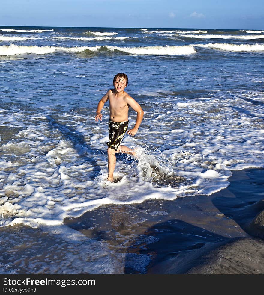 Young boy enjoys the waves of the blue sea