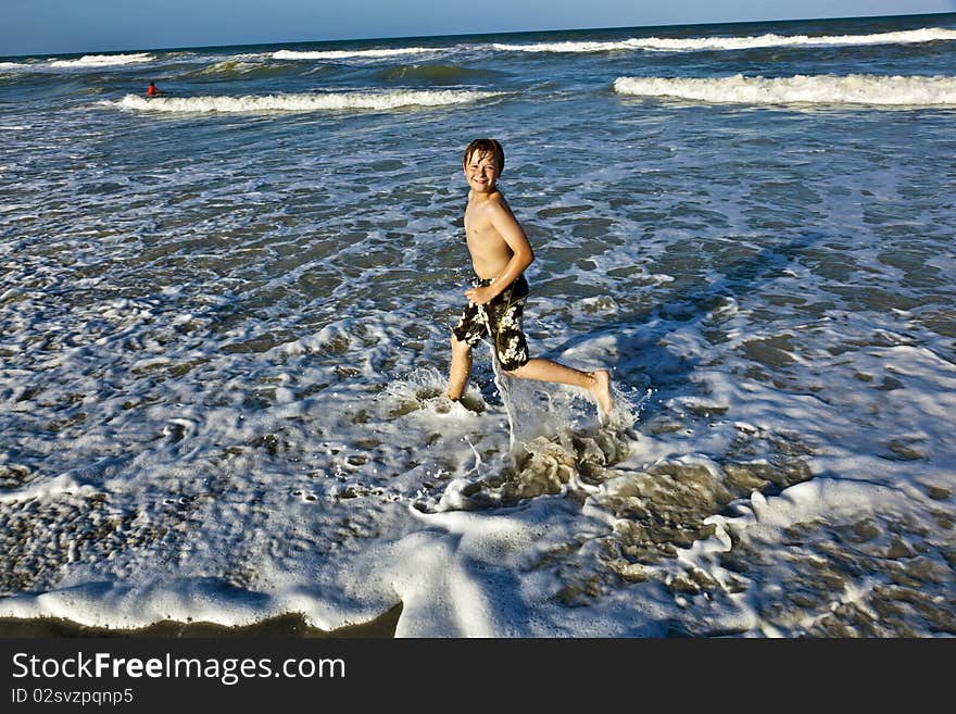 Young boy enjoys the waves of the blue sea