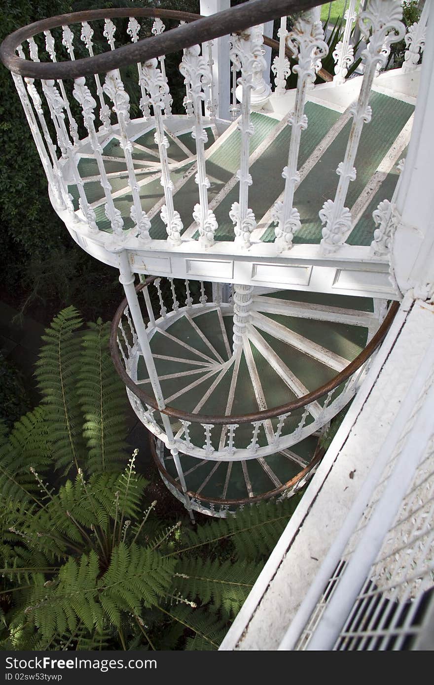 A view from above of a white metal spiral staircase in victorian style. A view from above of a white metal spiral staircase in victorian style