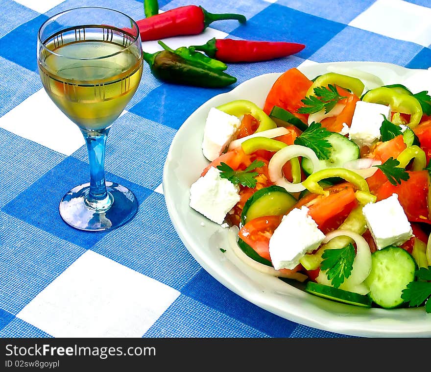 Salad of tomatoes, cucumbers, cheese and a cup of brandy on the cover of blue and white squares. Salad of tomatoes, cucumbers, cheese and a cup of brandy on the cover of blue and white squares