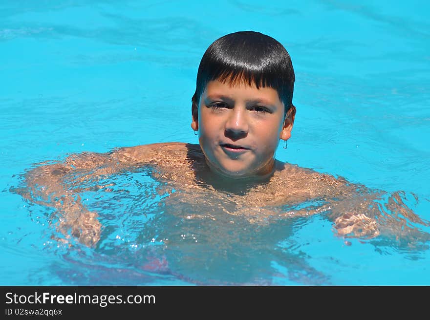 A Hispanic boy is swimming in a summer camp. A Hispanic boy is swimming in a summer camp